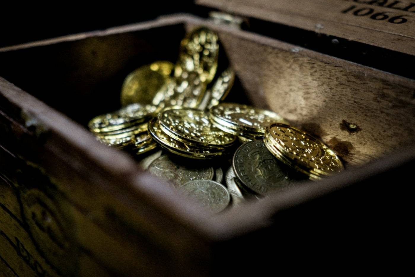 A wooden box full of old coins in low light